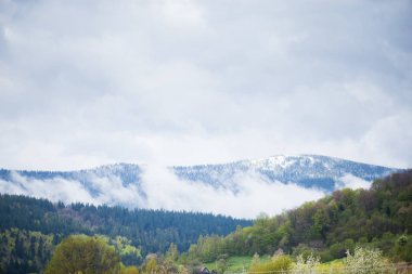 Karlar, ilkbahar günü, dramatik gökyüzü ile dağ manzarasını kapladı.