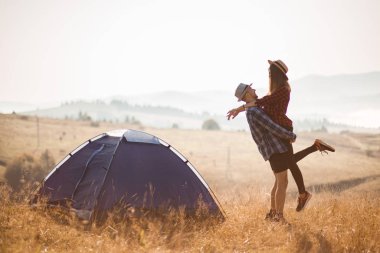 Sevgi dolu çiftlerin silueti sonbahar tatilinde kamp kurar. Dağın tepesinde..