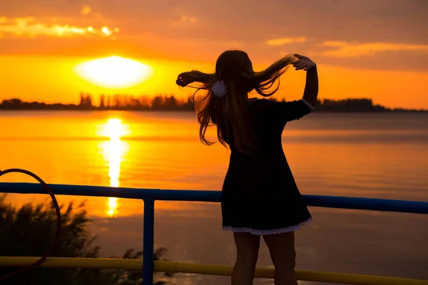 Vista lateral da luz traseira de uma silhueta mulher respirando ar fresco profundo ao nascer do sol quente na frente do sol. leveza e arejamento feminino — Fotografia de Stock