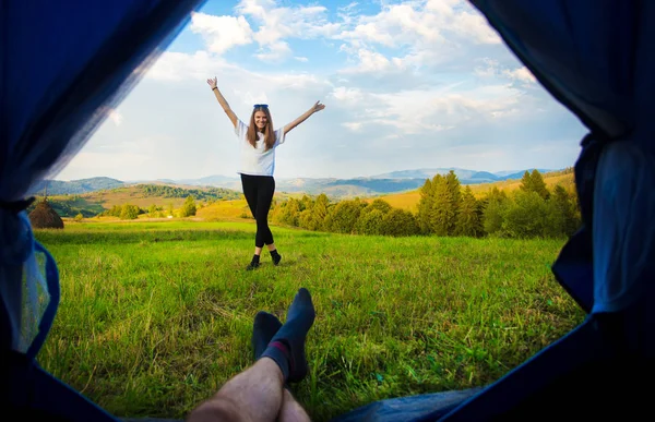 Man lying in tent and looking for his girlfriend with hands up, view from inside of tent. Hiking in mountains. — Stock Photo, Image