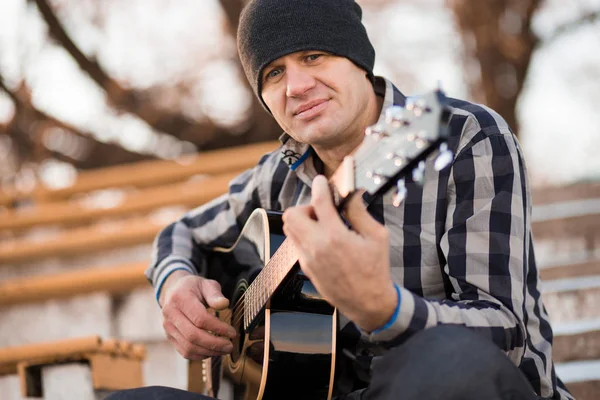 Joven sentado en los escalones tocando la guitarra y cantando, concepto musical — Foto de Stock