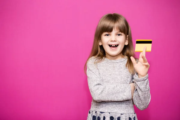 Ευτυχισμένο κοριτσάκι με νέα τραπεζική πιστωτική κάρτα και έτοιμο να πάει για ψώνια απομονωμένο σε ροζ — Φωτογραφία Αρχείου