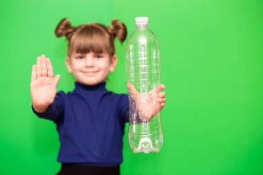 Little girl with plastic bottle and open hand say stop of plastic pollution, recycling plastic, plastic free isolated on green