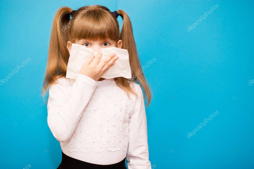 Cute little girl blowing out her nose isolated on blue background