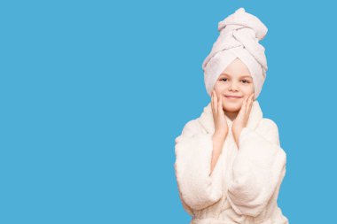 Güzellik tedavisinden sonra saç havlusu ve beyaz önlük giyen kaplıca güzeli kız. Mükemmel ciltli güzel bir kız çocuğu mavi arka planda izole edilmiş.