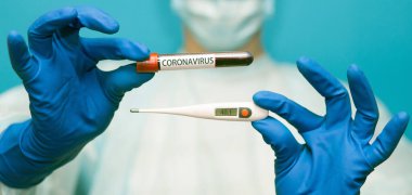 Koruyucu maskeli ve eldivenli doktorun pankart görüntüsü tıbbi termometre seti 40 ve mavi üzerinde izole edilmiş koronavirüs için kan testi yapılan test tüpü içeriyor. Coronavirus COVID 19 için hastaların kanını test ediyoruz..