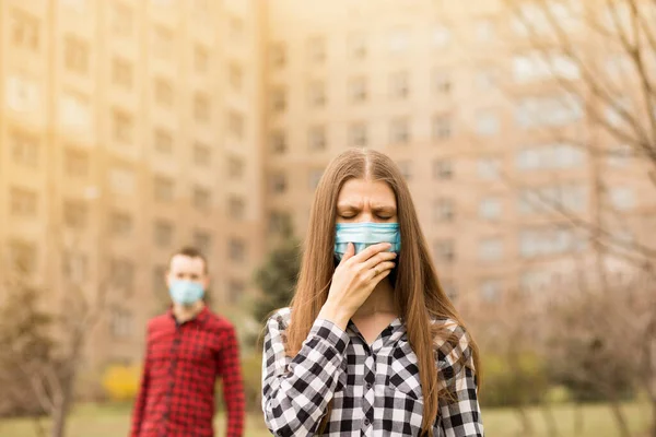 Young woman cough with medical mask against virus pandemic walking by street. Woman having symptoms like coughing and headache. Keep distance, keep calm