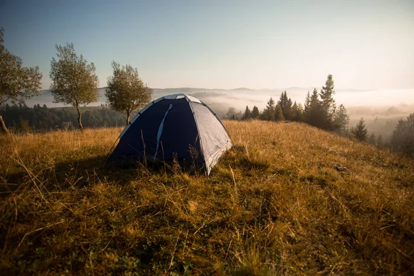 Morning landscape in mountains with tent. Camp rest in summer forest