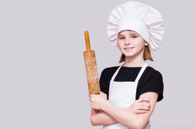 Şef üniformalı küçük bir kız, beyaz arka planda fotokopi alanı ile izole edilmiş merdane tutuyor. Aşçı çocuk. Pişirme Süreci Konsepti