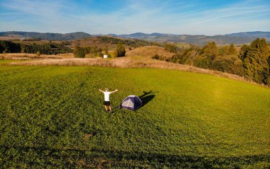 Gün batımında kamp yapan elleri havada bir adamın görüntüsü. Özgürlük