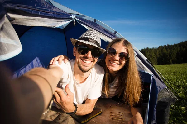 Camping funny couple in tent taking selfie. Happy friends having fun togheter. Concept active lifestyle and technology
