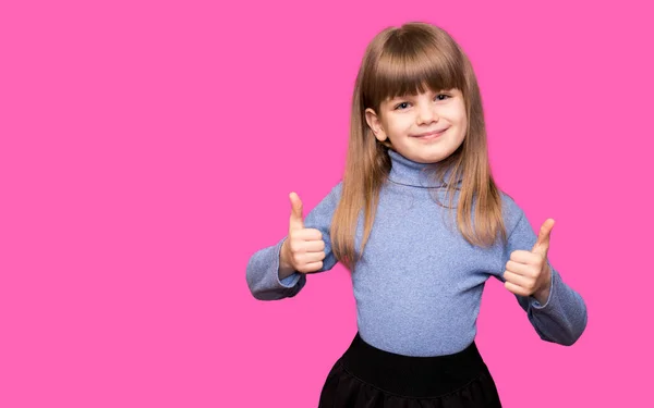 Ευτυχισμένο Κορίτσι Παιδί Μπλε Πουλόβερ Δείχνει Τους Αντίχειρες Και Κοιτάζοντας — Φωτογραφία Αρχείου