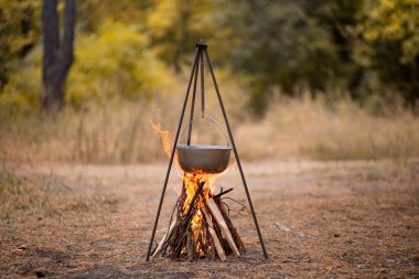 Sonbahar ormanlarında kamp ateşinde yemek hazırlamak.