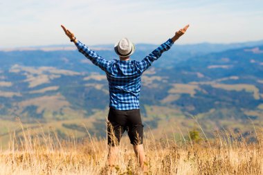 Elleri havada olan adam Karpat dağlarındaki güzel dağlara hayran.