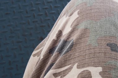 Kamuflaj pantolonunun detaylarında çelik plaka ve metal arka plan var.