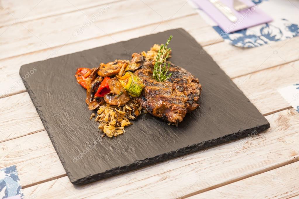 Grilled steak served with rice and vegetables on a graphite plate