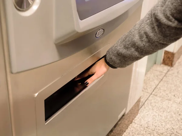 Girl\'s hand pick up a coin from a automated ticket vending machine for the metro station in Athens,Greece