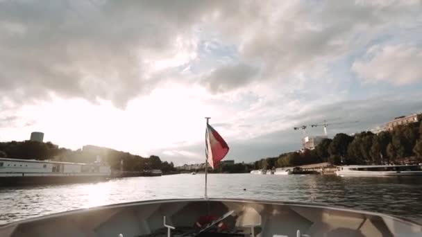 Brillante bandera francesa unida a la popa de un barco a motor. Nada en el pintoresco Sena de París. El puente está en primer plano., Panorama — Vídeo de stock