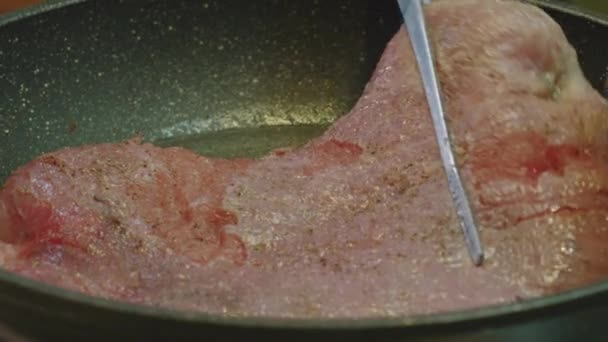 Faire tourner à la main le steak de porc frit dans une poêle. gros plan de steak . — Video