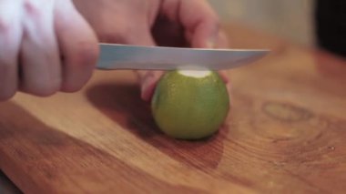 Erkek eli limonu dilimliyor, kahverengi tahtada, yakın plan, 2019