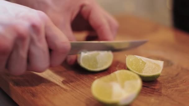Male hand slices lime, on brown board closeup, — 비디오