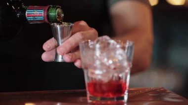 Barmen elin, greyfurtlu böğürtlenli smoothie hazırlarken yakın plan. İçindekileri bir kokteylin içine boşaltıyor.