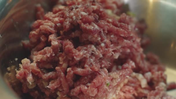 Szlifierka działa i przekręca surową mielonkę w zbliżeniu. Ujęcie z bliska mięsa mielonego jest przewijane przez maszynę do mielenia mięsa. — Wideo stockowe