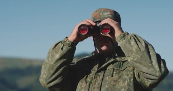 The hunter raised his binoculars, looking for his next destination in the mountains, close up — Stock Video