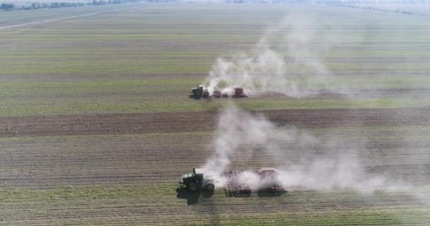 La caméra survole deux tracteurs travaillant sur le terrain, vue latérale — Video