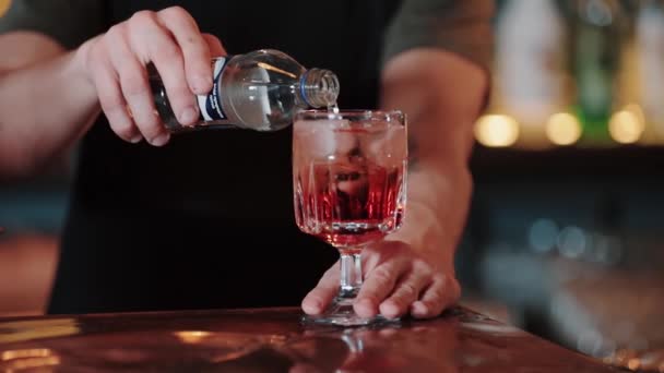 Een slow motion video van een mixoloog die een Aperol-Spritz cocktail maakt. schenkt, roeren de ingrediënten met een cocktail lepel — Stockvideo