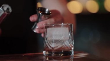 Barmen ölçü bardağından bardağa kokteyl doldurur. Eski moda. Kapat.