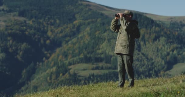 猎人举起双筒望远镜，寻找他在山上的下一个目的地- -总体计划 — 图库视频影像