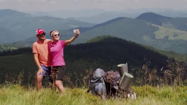 Man and woman model exterior with backpacks making selfie on mountain — Stock Video