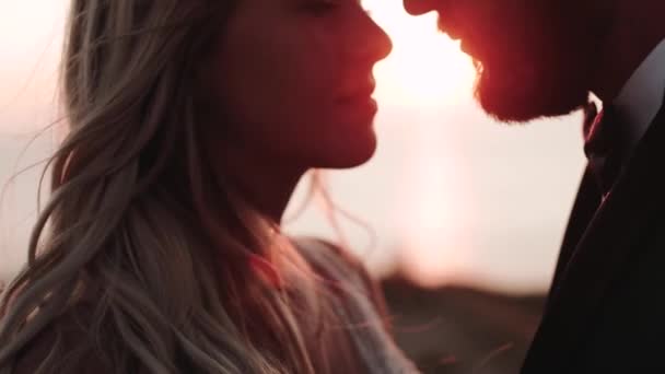 Gün batımının arka planında öpüşen kız ve erkek yüzlere odaklanıyor. Issız bir arazide romantik bir buluşma. Yakın plan. — Stok video