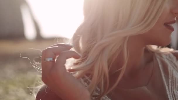 Blond girl straightens her hair at sunset. closeup. — Stock Video