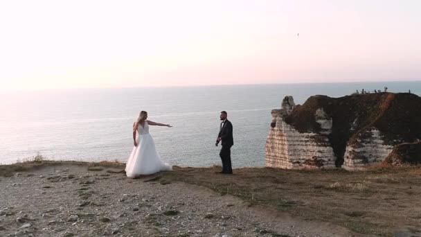 Etretat. Francie, Krásné nevěsty jsou fotografovány na pozadí přírody. Mladý pár kráčí podél nábřeží. Jemný výhled a krásné záběry oceánu. Zpomalený pohyb. — Stock video