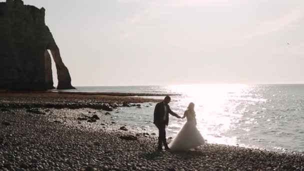 Etretat. Frankrijk, Jonge echtpaar wandelen langs de waterkant op — Stockvideo