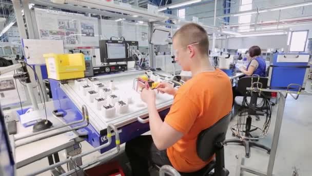 A young worker sits behind a car testing machine — Stock Video