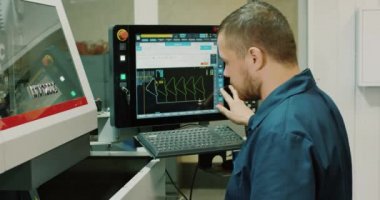 CNC değirmen makinesi operatörü atölyedeki bir bilgisayarda çalışıyor. RED EPIC-W 4K kamera ile çekildi.
