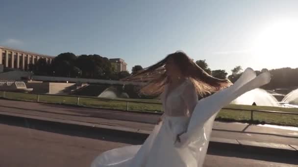 Молодая невеста бежит в замедленной съемке размахивая платьем и длинной вуалью на фоне Эйфелевой башни. Солнечный день. В Париж. Франция — стоковое видео