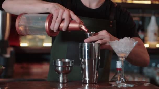 Бармен наливает алкоголь в мерную чашку и наливает его — стоковое видео