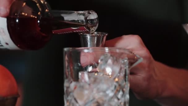 Häll whisky i en mätbägare och häll i ett glas is — Stockvideo