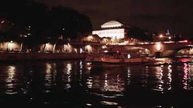 Önde bir deniz nehri ve bir tekne var. Gece çekiliyor. Paris