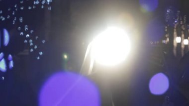 İki sevgili, şehrin renkli ultraviyole ışığında sarılıp öpüşüyor. Gökkuşağı simli neon ışıklı genç çiftin modern aşkı