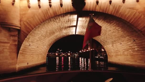 Drapeau français scintillant attaché à l'arrière d'un bateau à moteur sur fond de tour Elfel la nuit. le navire nage sous le pont — Video