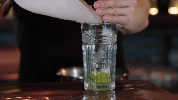 .Barkeeper gießt zerstoßenes Eis in ein Glas mit Zitrone. Nahaufnahme — Stockvideo