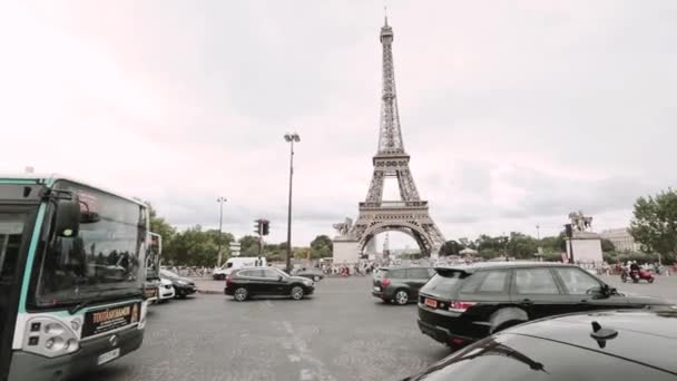 La Torre Eiffel con traffico. Cielo nuvoloso blu nella giornata estiva con alberi verdi, auto e persone che camminano intorno — Video Stock