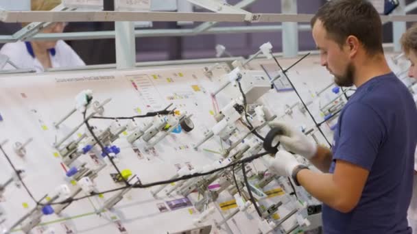 Fábrica de productos de cable. mujeres y hombres recogen cable y conectores a los coches — Vídeo de stock