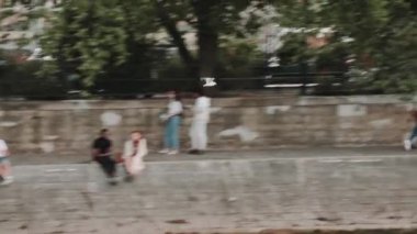 İnsanlar suyun kenarında oturuyorlar. Bir kuş Seine nehrinin yakınında uçuyor. Paris mi? Fransa