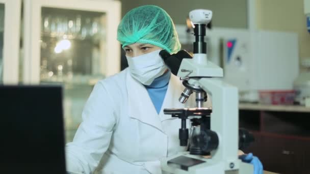 Mulher trabalhando em um laboratório ao microscópio — Vídeo de Stock